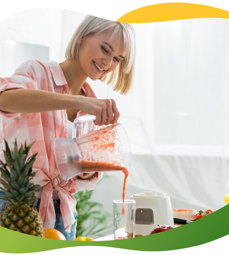 A blonde woman with a bob prepares her smoothie with pineapple and various fruits